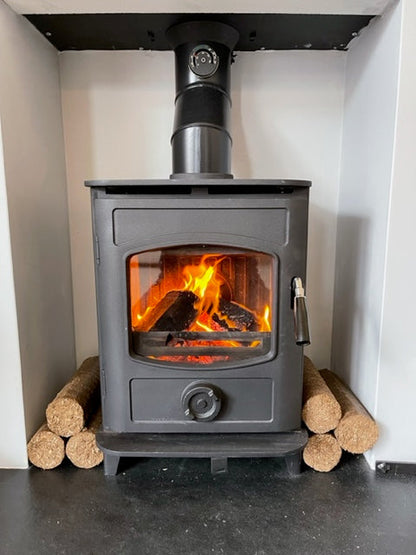 Long Burn Nestro Natural Wood Fuel Briquettes stacked next to a wood stove