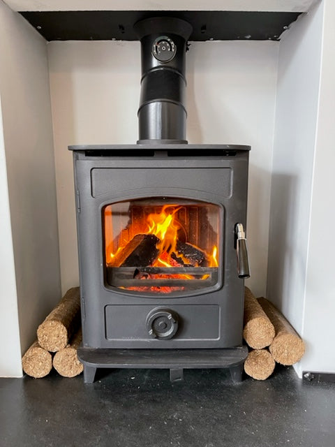 Long Burn Nestro Natural Wood Fuel Briquettes stacked next to a wood stove